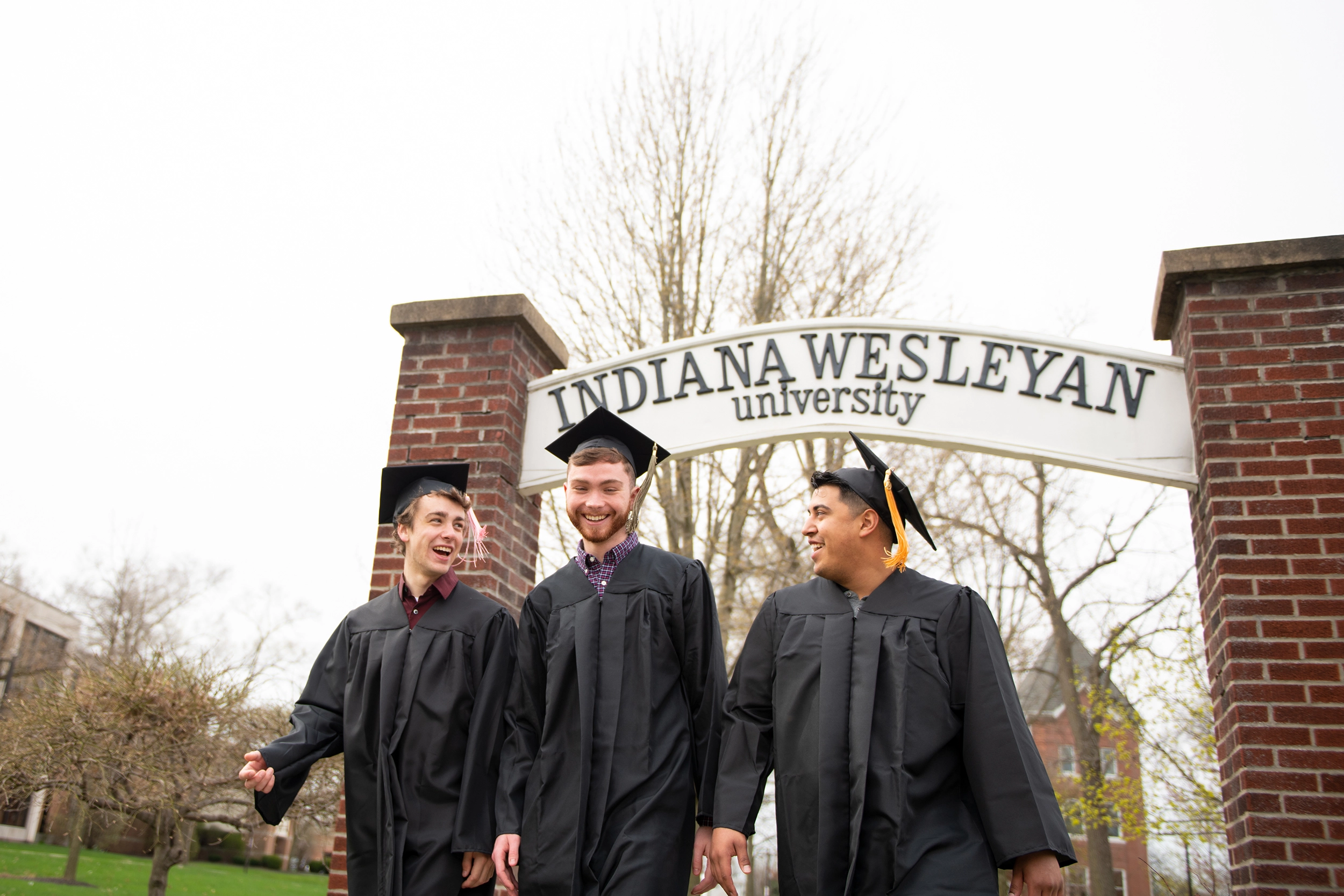 three graduates walking on campus